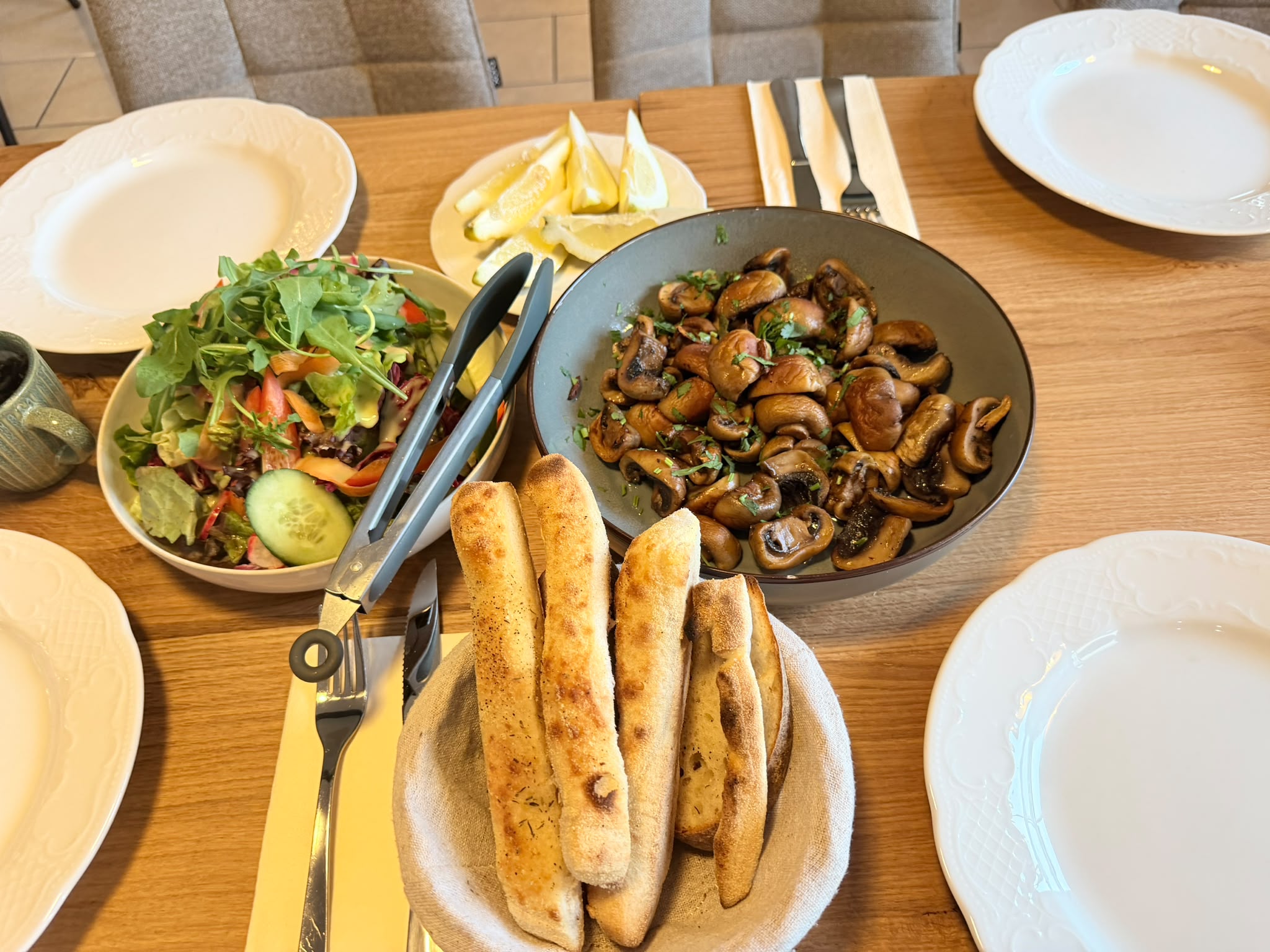 Gedeckter Tisch mit Salat, Pilzen und frischem Brot